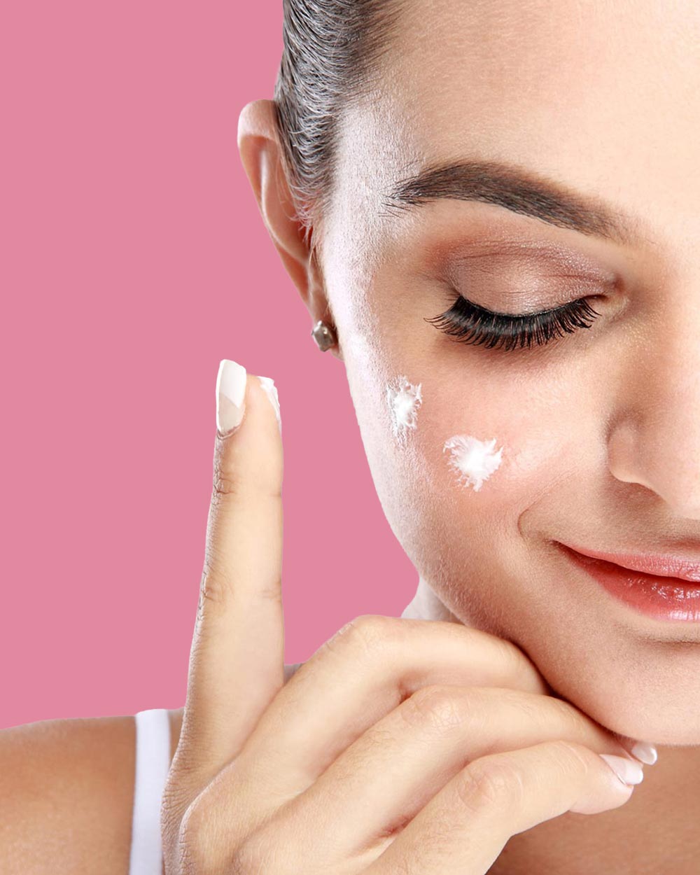 Frau mit Creme am Finger und Cremepunkten im Gesicht